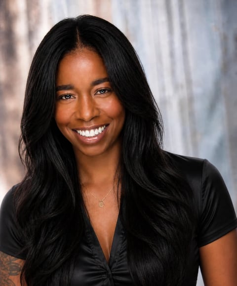 Professional headshot of a smiling woman with long black hair wearing a black shirt against a blurred background
